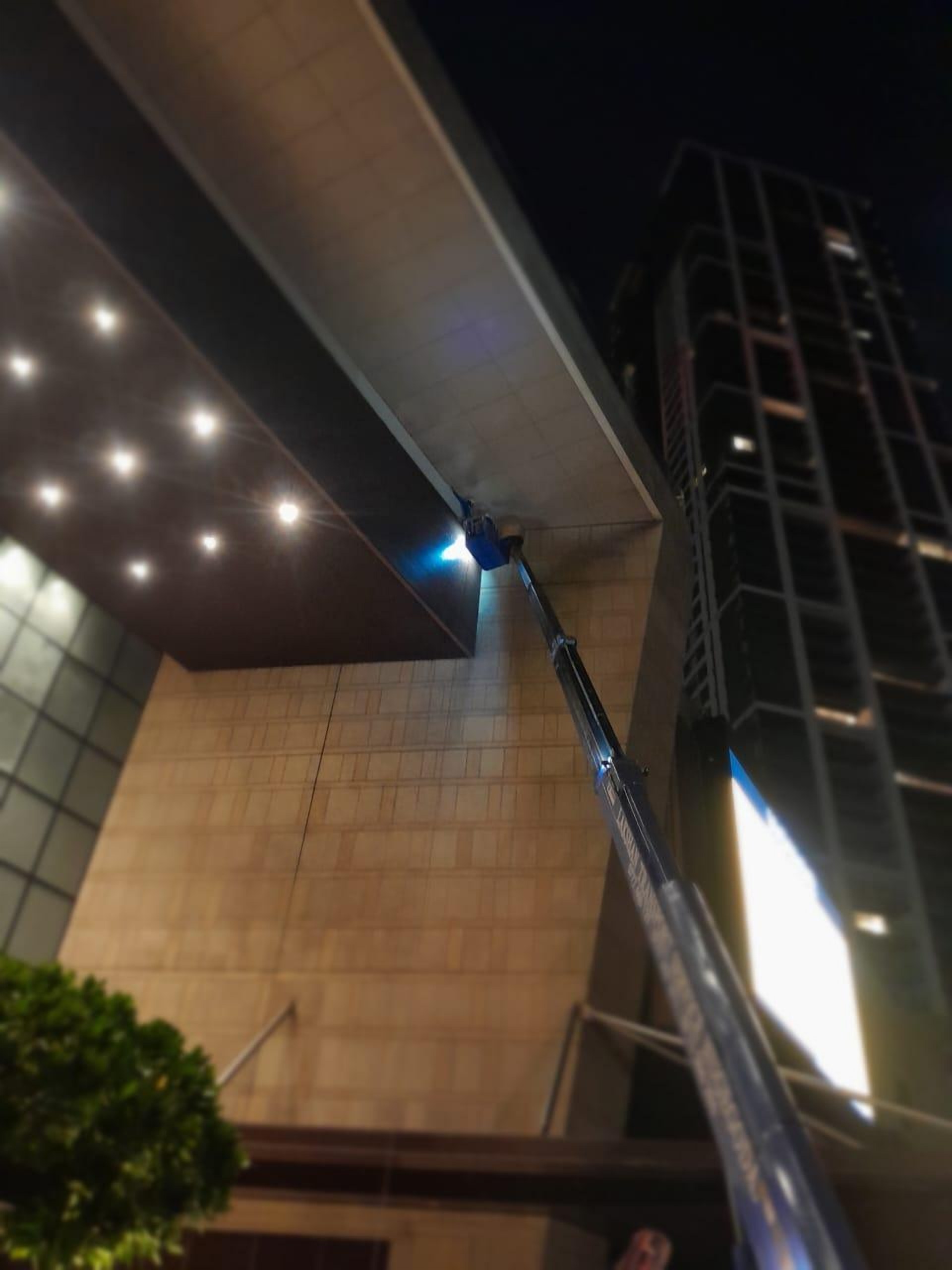 Boom truck reaching a building canopy at night
