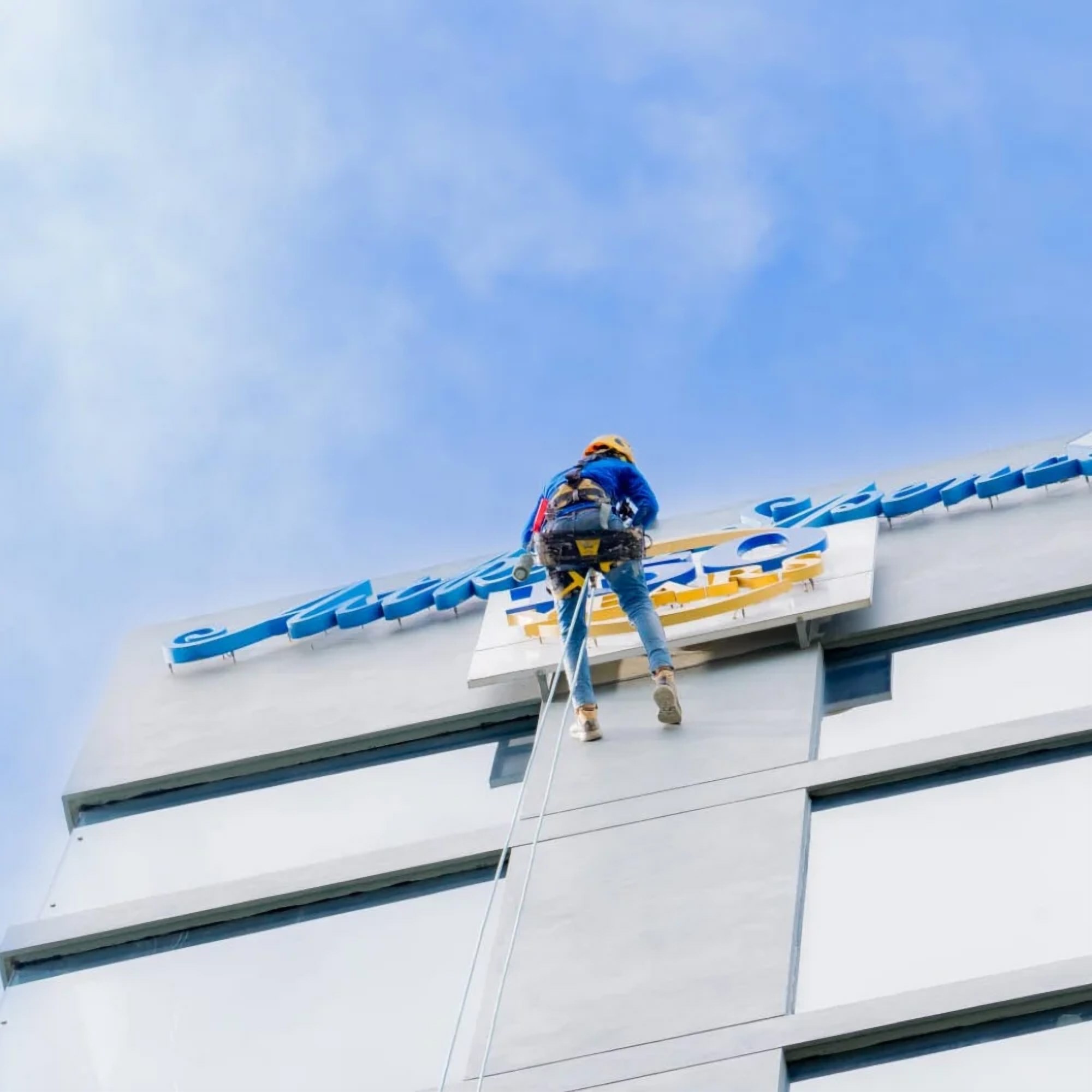 Rope access technician descending from a building's roof edge