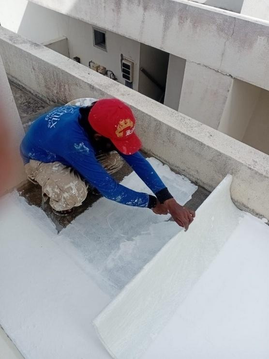 Technician applying waterproofing to a parapet wall